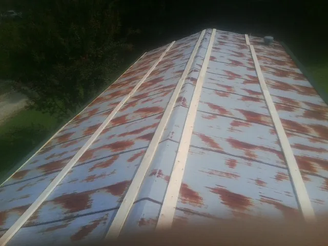 Rusted metal roof panels with new wood purlins before replacement — Storm Damage Roof Repair in Lynnville by Roofing Brothers