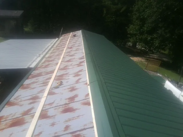 Old rusted panels beside newly installed green metal roofing — Wind Damage Roof Repair by Roofing Brothers in Lynnville